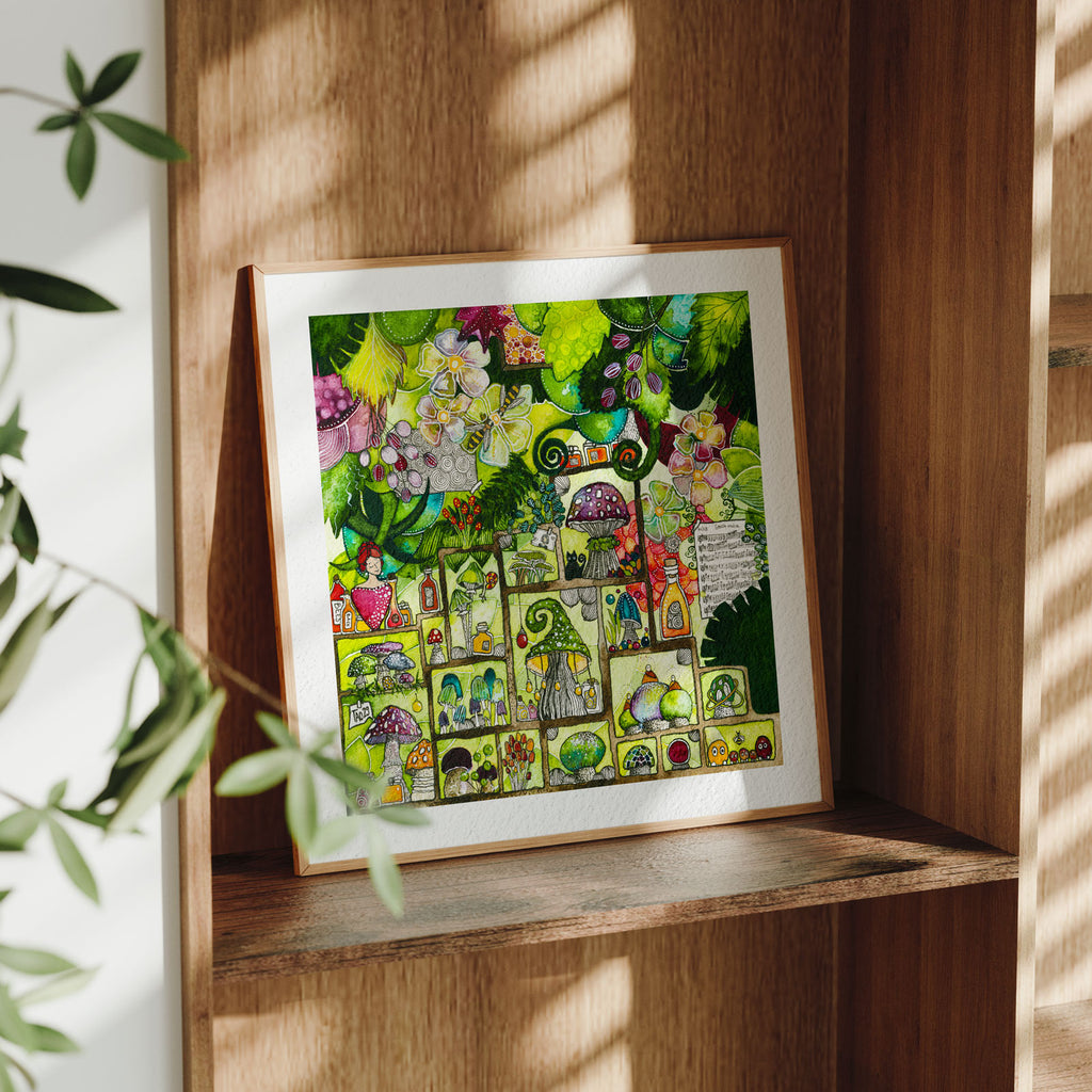 Framed fine art print of After Rain, a maximalist green watercolour of mushrooms, flowers and tiny cabinet scenes, in a light oak frame on a wooden shelf in dappled sunlight