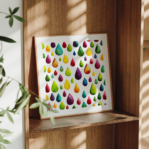 Framed Flow fine art print leaning on a wooden shelf in dappled daylight, a scatter of jewel-toned watercolour raindrops on white paper, from Léna Ruisz's Materia collection.