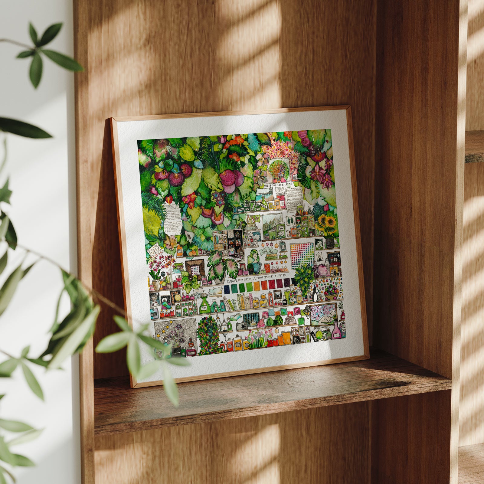 Framed Green Cabinet fine art print leaning on a wooden shelf in dappled daylight, cascading green foliage above shelves crowded with bottles, tiny framed paintings and a colour grid, from Léna Ruisz's Cabinet of Small Worlds collection.
