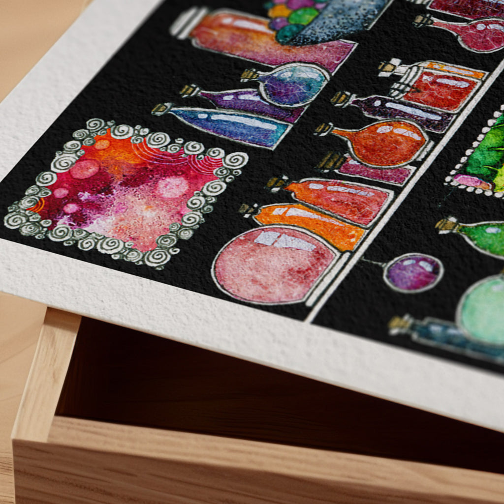 Detail of the Sorceress' Cabinet fine art print resting on a wood surface, showing the deckle paper edge and close-up of glowing apothecary bottles in watercolour and ink on a black ground