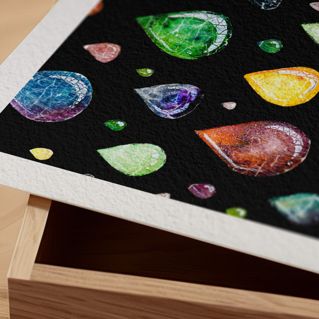 Detail of the Still Falling fine art print resting on a wood surface, showing the deckle paper edge and close-up of translucent jewel-toned raindrops with veined interiors falling against a black ground in watercolour and ink